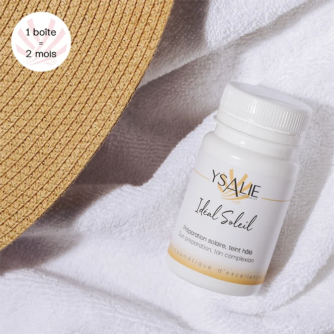 Complément alimentaire Idéal Soleil Protection solaire et bronzage, sur une serviette blanche à côté d'un chapeau